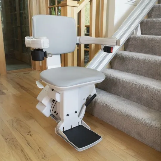 Bruno Elite Straight stairlift installed on indoor stairs with beige upholstery, showing comfortable seat and handrails for safe stair access